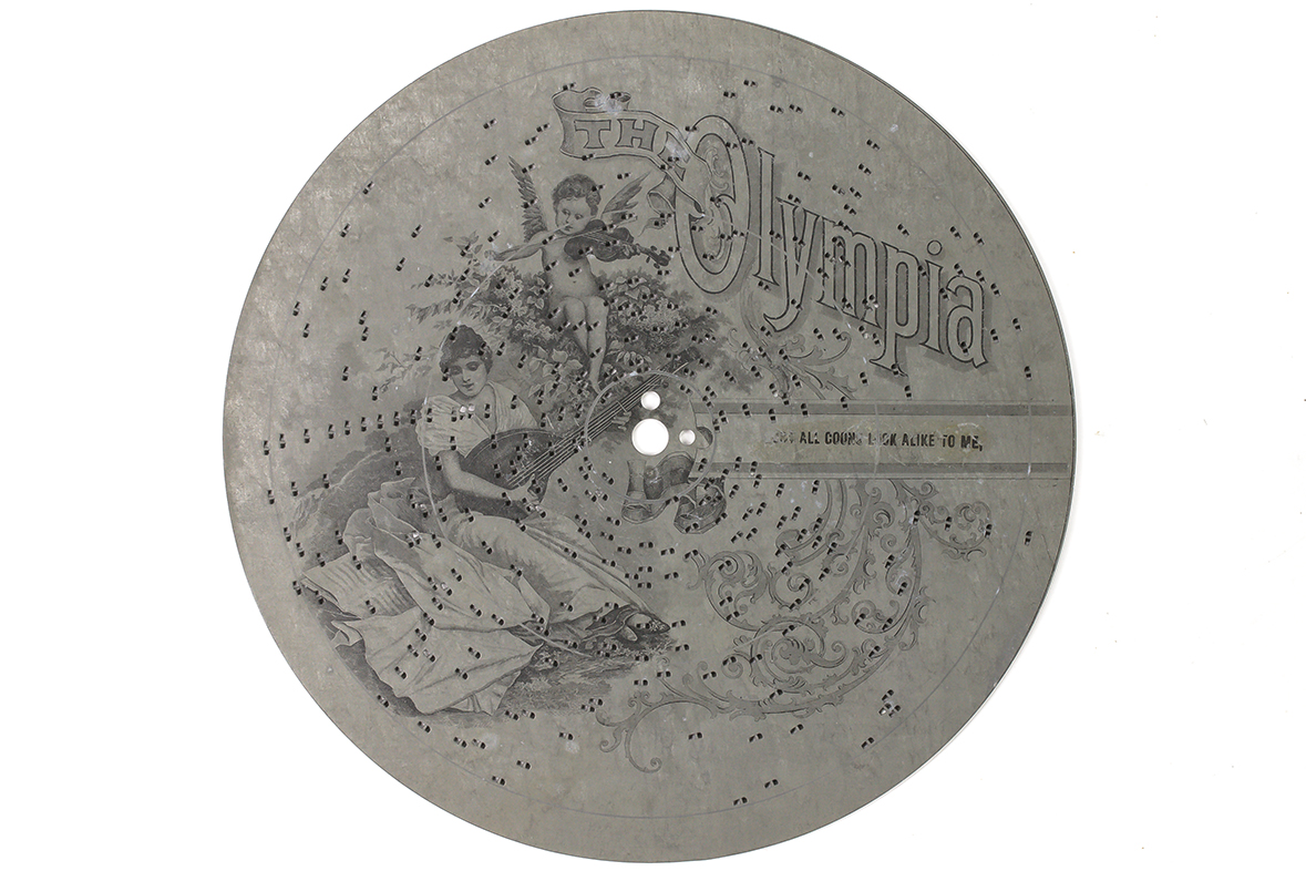 Steel disc with punched out pins and attractive illustration printed on face for the Olympia music box