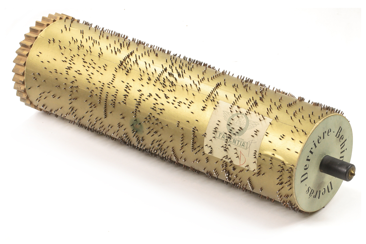 Large wooden cylinder covered in gold-colored foil with metal pins for the Faventia Street Piano