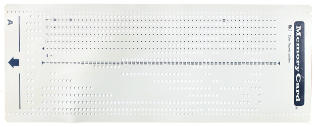 A sheet of plastic punched with holes making a pattern for a knitting machine